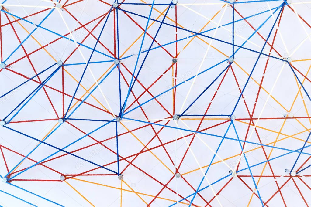 Abstract colored threads are stretched on pins on white background depicting ties and knots. Logistic grid, geometric, connections, isometrics and spirograph
