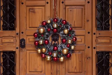 Kırmızı kurdele, Noel topları ve çan ile geleneksel Noel köknar çelenk. Ön kapı eşik Noel dekorasyon