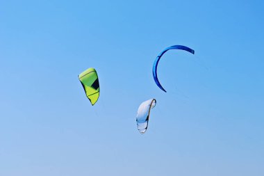 Renkli uçurtma Kiteboarding grup tarafından rüzgar estigi mavi gökyüzünde uçuyor. Aktif eğlence ve yaz spor kavramı