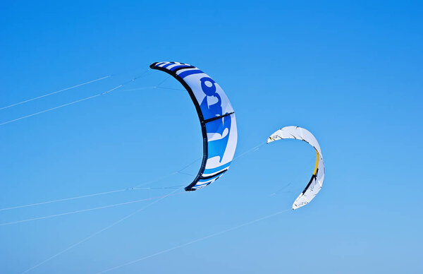 Two colorful kites of kiteboarding is flying in the blue sky by the wind blow. Active pastime and summer sports concept
