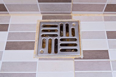 Dirty stainless steel bath shower drain in modern style. Wet shower drain with unhygienic trash, top view