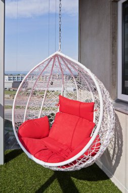 Kırmızı yastık modern rahat asılı sandalyeyle şehrin muhteşem manzarası ile görünümü bir balkon