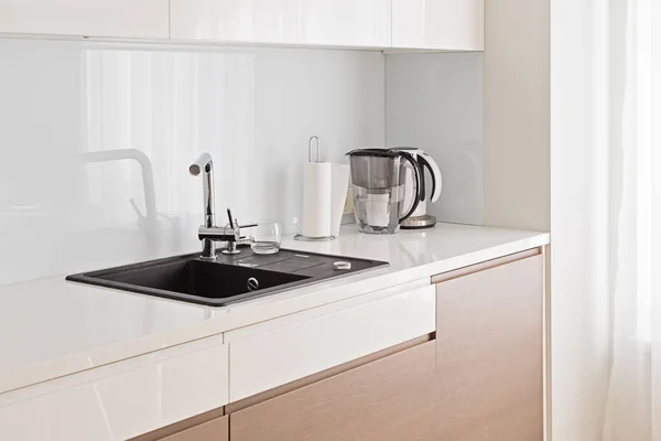 View of modern spacious and light kitchen with dark sink and beige cupboard with copy space — Stock Photo, Image