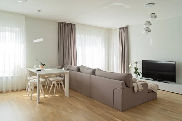 Vue sur grand salon moderne et lumineux avec canapé beige confortable et table à manger — Photo