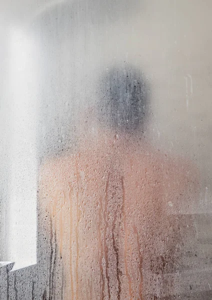 Silhouette of adult man in shower cabin