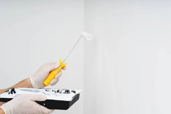 Coseup paint roller in hand with white paint on clean wall — Stock Photo, Image
