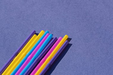 Mor arka planda renkli tek kullanımlık plastik pipetler