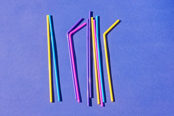 Colored disposable plastic straws on purple background