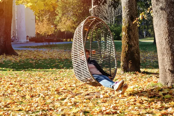 女孩在秋天公园摆动挂藤椅 — 图库照片