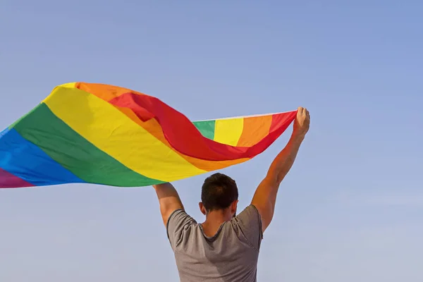 Lgbt gökkuşağı bayrağı sallayarak ellerini kaldıran adam — Stok fotoğraf