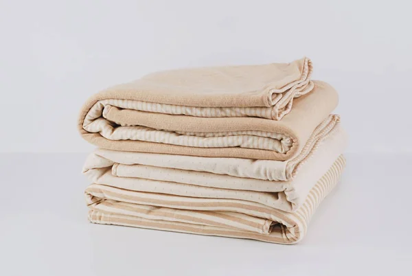 Closeup pile wrapped folded natural beige cotton blanket on white — Stock Photo, Image