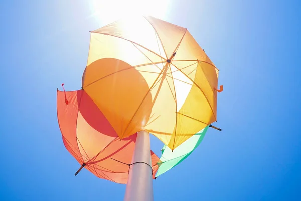 Kolorowe parasole na lampie ulicznej przeciwko błękitnym niebem — Zdjęcie stockowe