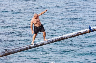 Rakip yağ ve yağ kaplı ahşap kutup üzerinde Gostra bayrak kapmak için çalışır