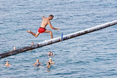 Rakip yağ ve yağ kaplı ahşap kutup üzerinde Gostra bayrak kapmak için çalışır