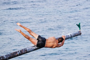 Rakip yağ ve yağ kaplı ahşap kutup üzerinde Gostra bayrak kapmak için çalışır