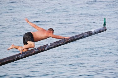 Rakip yağ ve yağ kaplı ahşap kutup üzerinde Gostra bayrak kapmak için çalışır