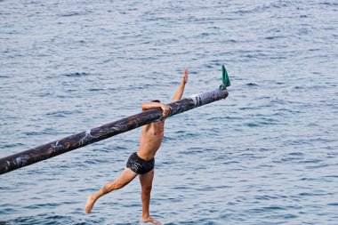 Rakip yağ ve yağ kaplı ahşap kutup üzerinde Gostra bayrak kapmak için çalışır