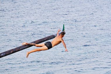 Rakip yağ ve yağ kaplı ahşap kutup üzerinde Gostra bayrak kapmak için çalışır