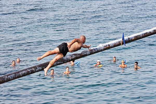 Competitor tries to grab flag on Gostra on wooden pole covered in grease and fat