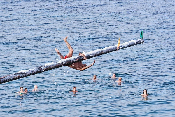 Ανταγωνιστής προσπαθεί να αρπάξει σημαία στο Gostra σε ξύλινο πόλο καλυμμένο με λίπος και λίπος — Φωτογραφία Αρχείου