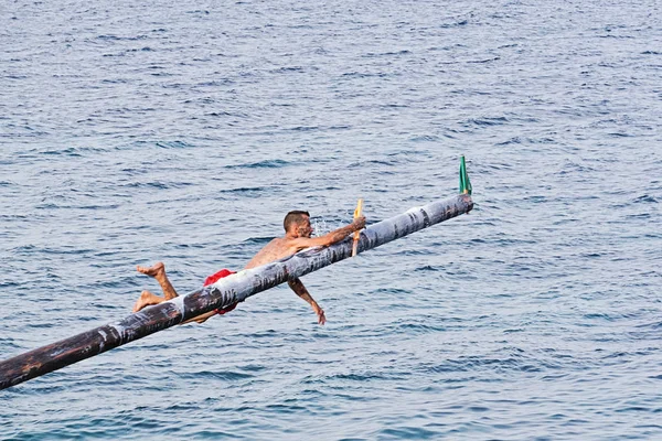 Ανταγωνιστής προσπαθεί να αρπάξει σημαία στο Gostra σε ξύλινο πόλο καλυμμένο με λίπος και λίπος — Φωτογραφία Αρχείου
