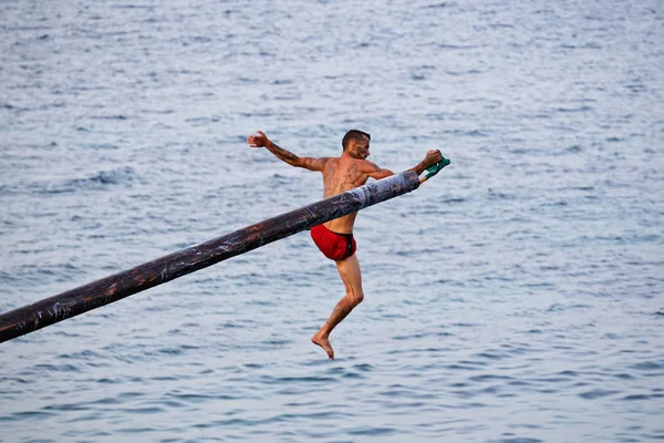 Il concorrente cerca di afferrare bandiera su Gostra su palo di legno ricoperto di grasso e grasso — Foto Stock