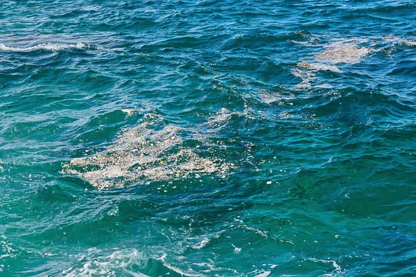 Türkisfarbene Meerwasseroberfläche mit schwimmenden Trümmern, Plastikstücken — Stockfoto