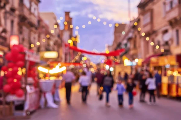Desenfocado multitud de personas durante la feria de Navidad una calle del casco antiguo con luces de Navidad de colores — Foto de Stock