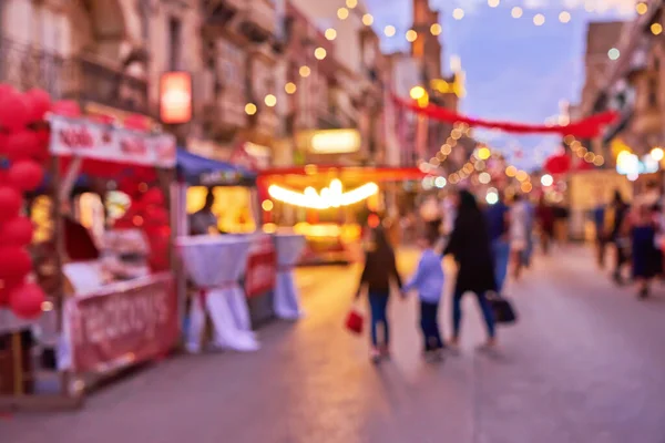 Silueta desenfocada de la familia durante la feria de Navidad una calle de la ciudad con luces de Navidad de colores — Foto de Stock