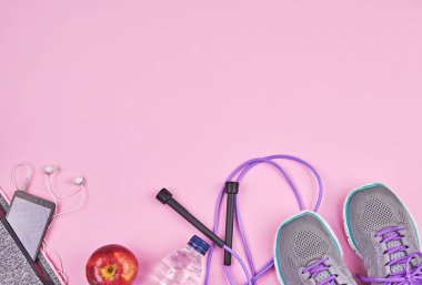 Spor aletleri ve aksesuarlar pembe arka planda, düz yerde fotokopi alanı ile. Evde online egzersiz, koşu ya da yoga egzersizi. Karantina sırasında kilo kaybı kavramı