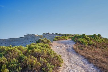 Marsaskala yakınlarındaki deniz kıyısındaki uçurum boyunca toprak yol manzarası,