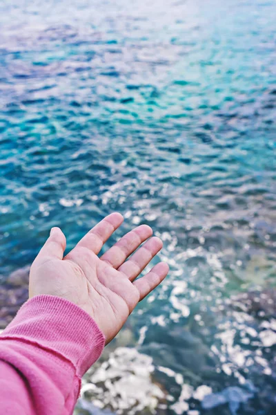 Weibliche Hand mit offener Handfläche greift nach Wasseroberfläche — Stockfoto