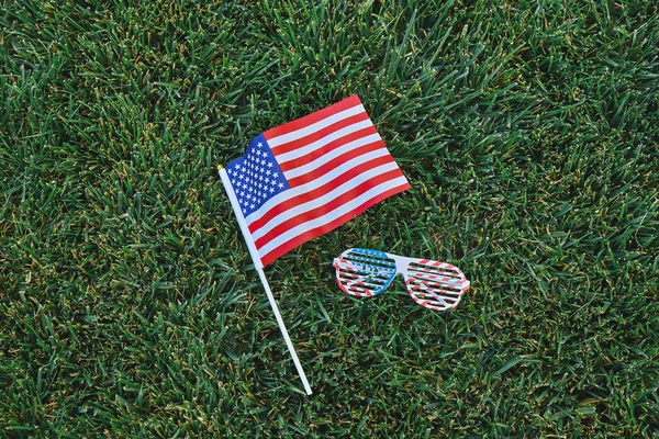 American flag and eyeglasses on green grass backgroun — Stock Photo, Image