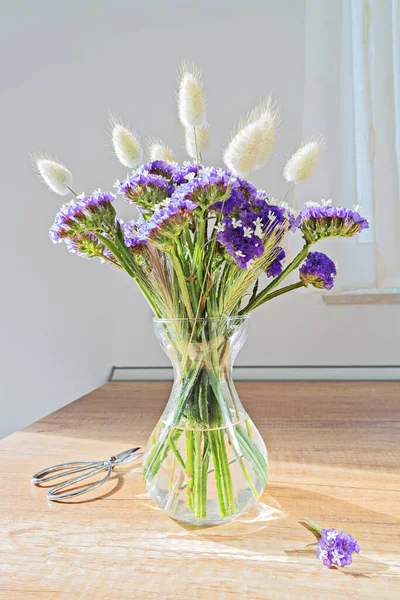 Szklany wazon z niebieskimi dzikimi kwiatami na drewnianym stole — Zdjęcie stockowe