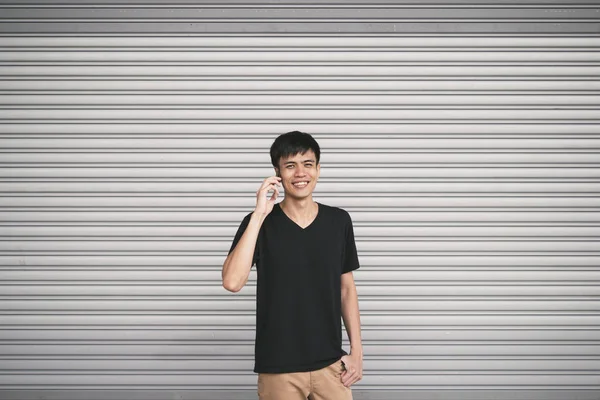 Молодой Азиат Мобильным Телефоном Позирующий Против Серой Стены — стоковое фото