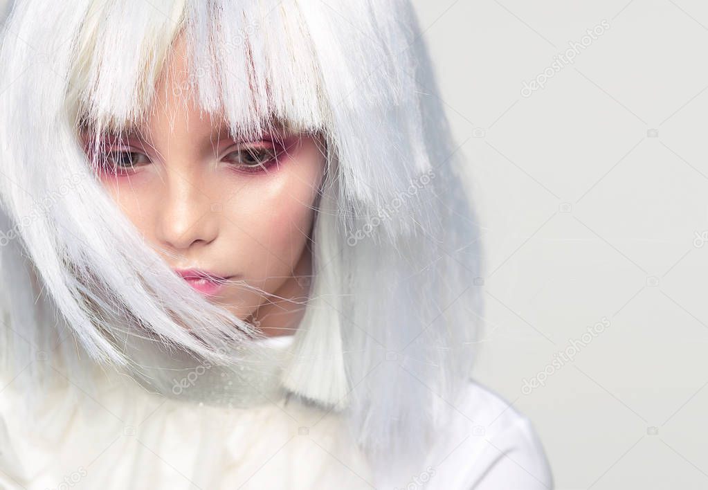 Girl in a white wig with flowers. Makeup.