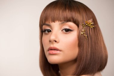 Yüzünü yaklaştır. Kısa saçlı bir kadının portresi. Saçında büyük kristallerle birlikte bir saç tokası var. Makyaj, siyah oklar ve inci rengi kahverengi gölgeler..