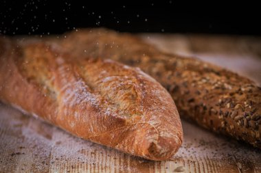 Kırsal ahşap masa üzerinde ay çekirdekli taze baget ekmeği ve diğer tohumların Macro manzarası..