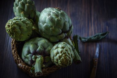 Kıvrımlı, sade bir arka planda, enginarların durgun yaşamı. Düşük tuşlu yumuşak odaklanma.