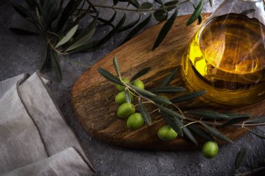 Kırsal arka planda zeytin dalıyla cam şişede ekstra saf zeytin yağı. Dikkat çekmeden. görünümü kapat