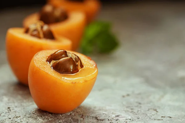 Taze taze Loquat Nispero gri arka planda naneli yapraklarla tatlandırılmış. Seçici odaklanma. Kapat..