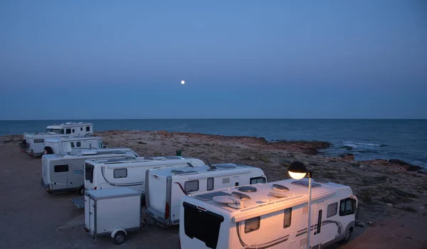 Akdeniz kıyısında gece vakti park etmiş bir karavan arabası ve karavan kampı. Güzel bir alacakaranlık ve ay ışığı.