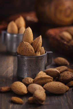 Antika metal bardaklardaki bademler koyu kırsal ahşap arka planda. Yan görüntüyü kapat..
