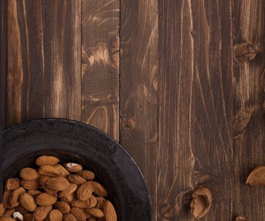 Kahverengi ahşap arka plan görünümlü diğer aksesuarlarla birlikte siyah tabakta düz badem yatıyordu. 3