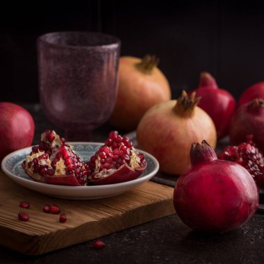 Koyu kırsal arka planda boş bir bardakla taze nar..