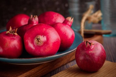 Kaba ahşap arka planda, tabakta olgun nar var..