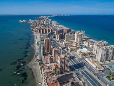 Akdeniz ve Mar Menor, Cartagena, Costa Blanca, İspanya arasında La Manga 'nın doğal bir tükürüğündeki yüksek binaların ve plajın havadan çekilmiş fotoğrafı..