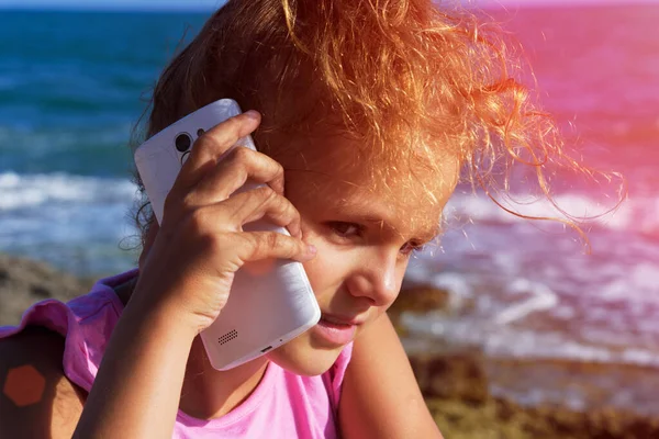 Pretty Little Girl Speaks Smartphone Squinting Sunshine Sea Background Sunset — Stock Photo, Image