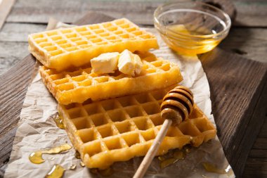 Lezzetli waffle balı ve bir dilim tereyağlı tabak. Ahşap bir arka planda. Yakın plan.