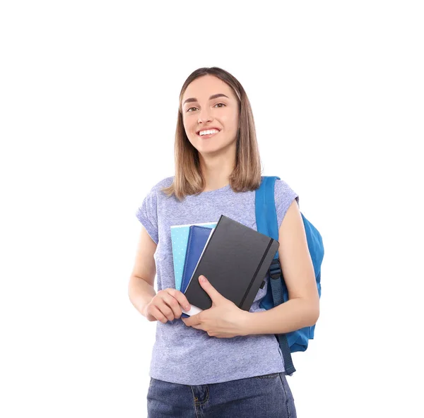 Sırt çantalı güzel bir kız öğrenci beyaz bir arka planda izole edilmiş defterleri elinde tutuyor.